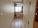 Narrow hallway with pink tiled flooring and wooden doors leading to different rooms