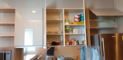 Open kitchen cabinets with various items and a stainless steel refrigerator