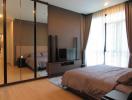 Modern bedroom with large bed, mirrored closet, and entertainment system