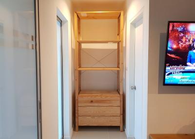 Compact living space with wooden shelving unit and wall-mounted television