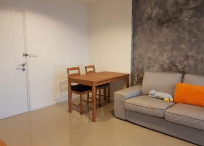 Modern living room with concrete accent wall, wooden dining table, and comfortable sofa