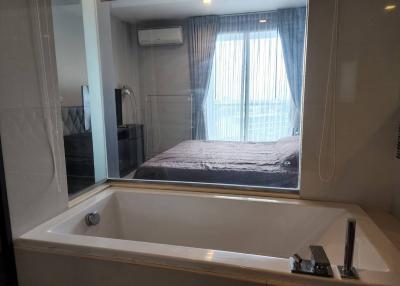 Modern bathroom with a large bathtub and a view into the bedroom