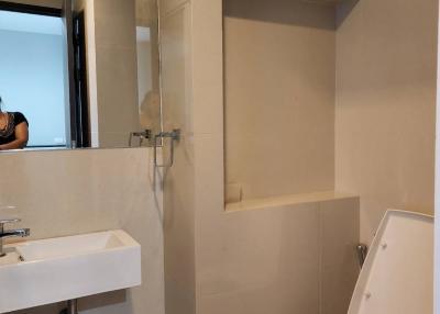 Modern compact bathroom with wall-mounted sink, toilet, and shower