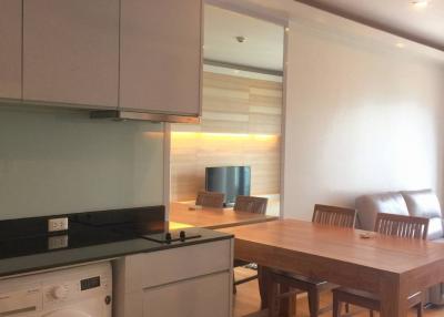 Modern kitchen with integrated appliances and adjacent dining area with wooden table and chairs