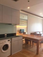 Modern kitchen with integrated appliances and adjacent dining area with wooden table and chairs