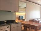 Modern kitchen with integrated appliances and adjacent dining area with wooden table and chairs