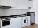 Modern kitchen with white cabinetry, appliances and washing machine