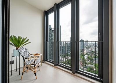 Modern balcony with cityscape view featuring high-rise buildings, a stylish chair and a green plant