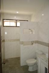 Modern bathroom with tiled walls, window, and sanitary fixtures
