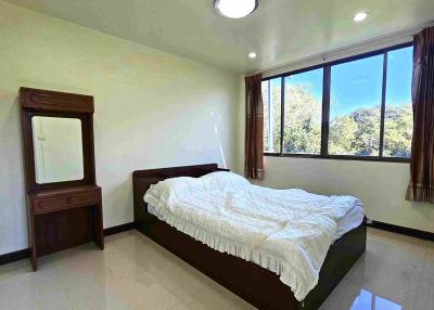 Bright spacious bedroom with large window and tiled flooring