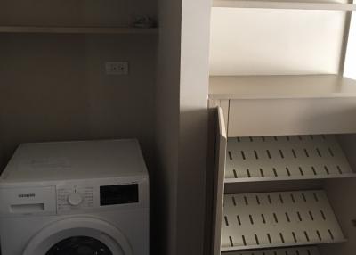 Compact laundry room with modern washing machine and built-in shelving