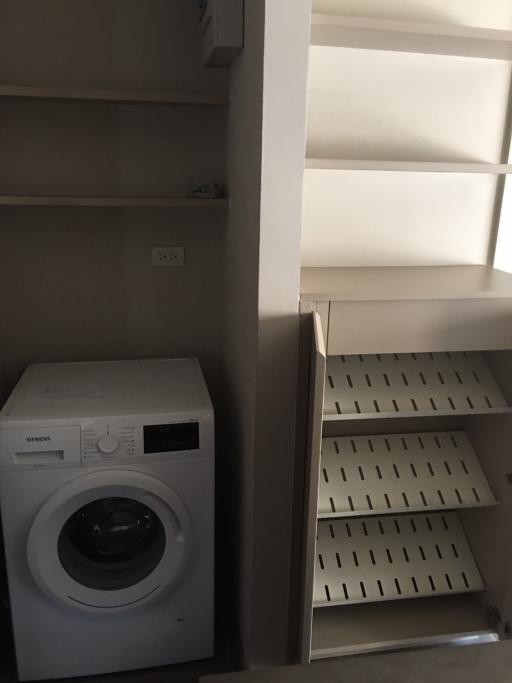 Compact laundry room with modern washing machine and built-in shelving