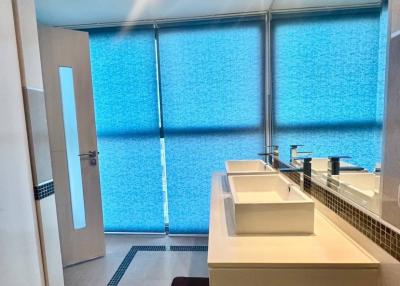 Modern bathroom with dual sink and blue privacy glass