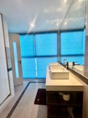 Modern bathroom with dual sink and blue privacy glass