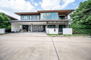 Modern two-story house with spacious driveway and lush greenery