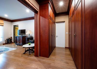 Spacious hallway leading to different rooms with hardwood floors and large wooden wardrobe