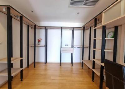 Spacious unfurnished office space with wooden flooring and shelf units