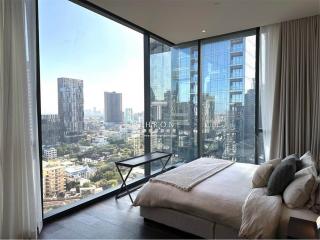 Modern bedroom with floor-to-ceiling windows overlooking the city