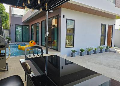 Modern outdoor patio with a swimming pool and barbecue grill