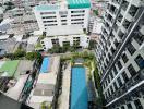 Aerial view of cityscape with swimming pool between buildings captured from a high-rise apartment balcony