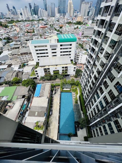 Aerial view of cityscape with swimming pool between buildings captured from a high-rise apartment balcony