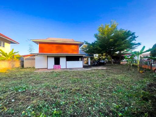 Spacious detached house with orange roof, large front yard, and a clear sky