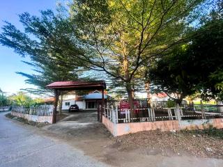 Spacious driveway leading to a residential house with carport and lush green trees