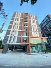 Modern multi-story residential building with glass entrance and distinctive orange accents