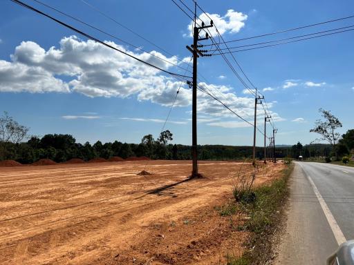 Vacant land plot beside a road under a clear blue sky