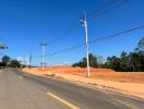 paved road next to a construction site under a clear blue sky