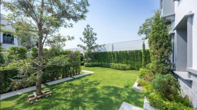 Lush garden with manicured lawn and mature trees next to a modern building