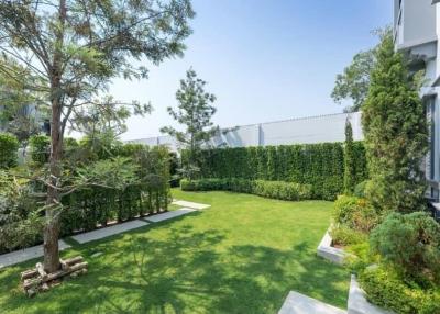 Lush garden with manicured lawn and mature trees next to a modern building