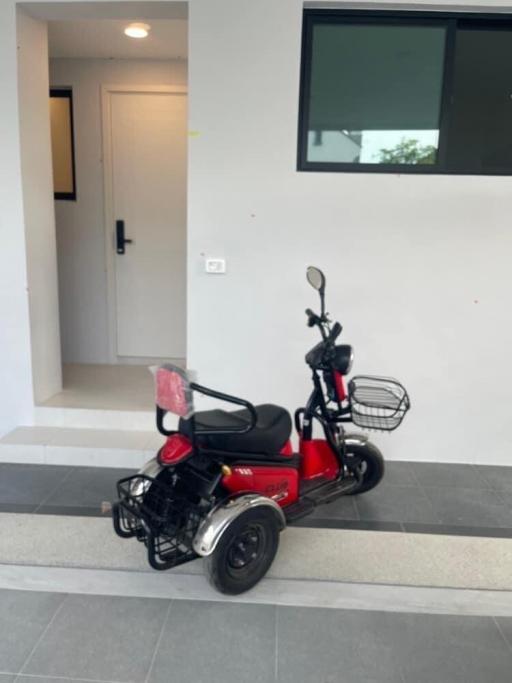 Electric scooter parked at the entrance of a modern home with white walls and a door in the background