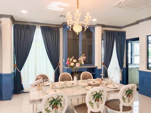 Elegant dining room with a large table set for a meal, chandelier, and blue drapes