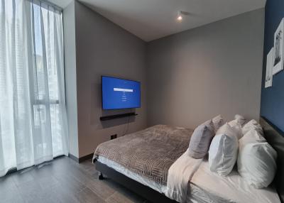 Modern bedroom with a large bed, wall-mounted TV and natural light from window