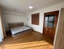 Bright bedroom with wooden flooring and large window