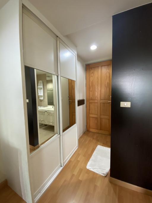 Hallway interior with mirror sliding door and wooden entrance door