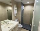 Modern bathroom interior with beige tiles, white vanity, and walk-in shower