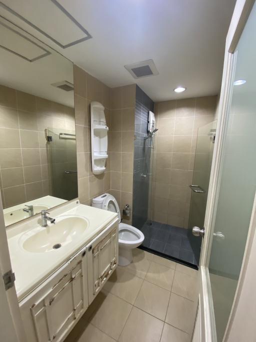 Modern bathroom interior with beige tiles, white vanity, and walk-in shower