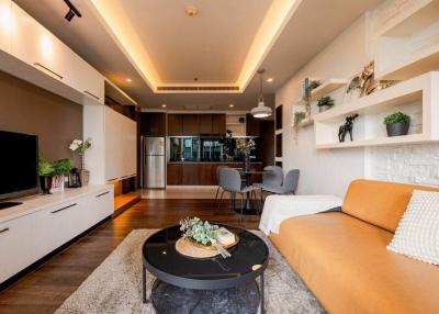 Modern living room with open kitchen design, featuring warm lighting and comfortable furnishings