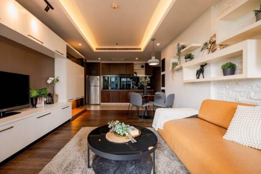 Modern living room with open kitchen design, featuring warm lighting and comfortable furnishings