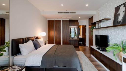 Modern bedroom interior with king-sized bed, TV, and hardwood finishing