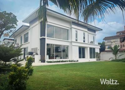 Modern two-story house with large windows and a spacious lawn area