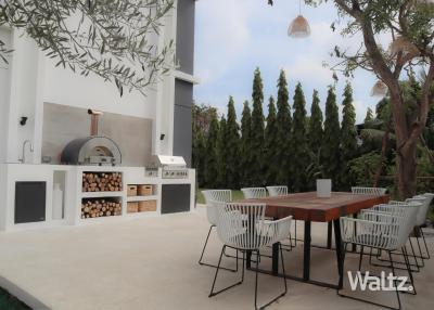 Modern outdoor kitchen and dining area with pizza oven and barbecue grill