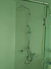 Modern shower with versatile shower head in a tiled bathroom.