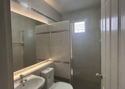 Compact modern bathroom with white fixtures and tiled walls