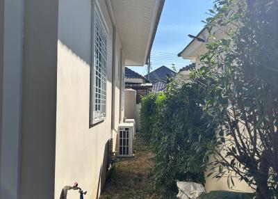 Side yard of a residential home with plants and exterior unit