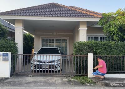 Suburban house with car parked in driveway and person near the gate