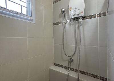 Modern bathroom with wall-mounted water heater and handheld shower