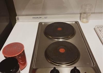 Close-up view of a stainless steel electric stove top with cooking controls and spice jars